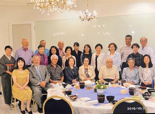 Group of people enjoying a joyful gathering around a table filled with food and drinks.