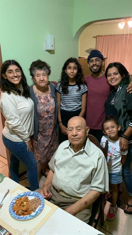 A loving family shares a meal, smiling and cherishing their time together.