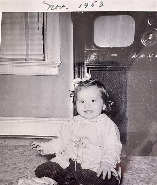 A baby sitting on the floor in front of a television