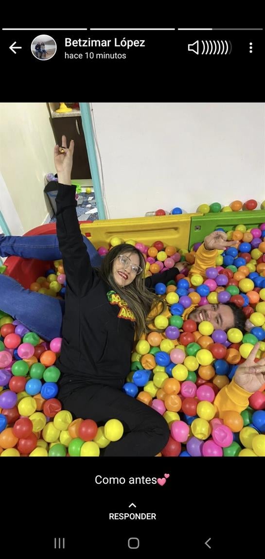 A person enjoys relaxing in a vibrant ball pit filled with colorful plastic balls.