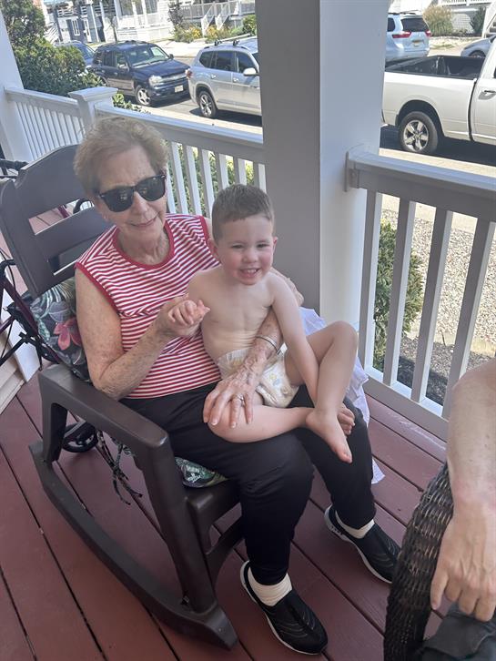 An older woman holding a young boy on a porch