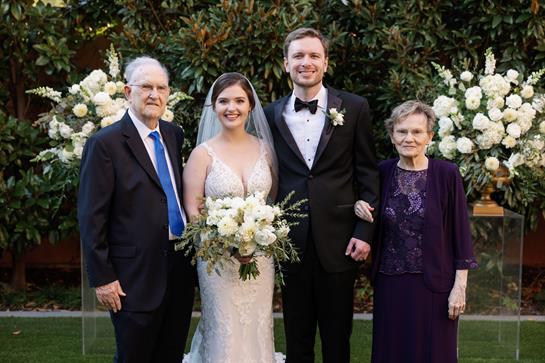 Newlyweds pose with their grandparents, showcasing love and joy during their wedding celebration.