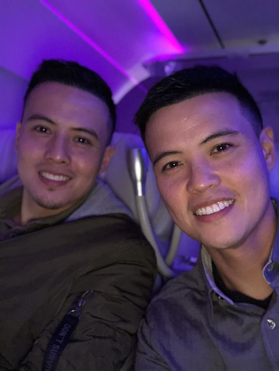 Two friends share a cheerful smile while seated on a flight, surrounded by colorful lights.