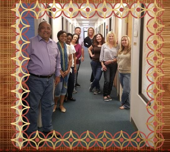 Individuals gather in an office hallway, smiling and enjoying a team-building moment together.