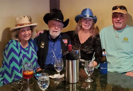 Friends gather around a table, sharing laughter and drinks in a vibrant bar setting.