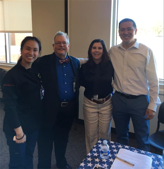 Four individuals smile and pose together, showcasing camaraderie at a professional gathering.