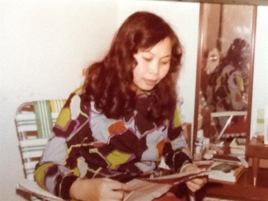 Woman reviews artistic materials in a vibrant outfit, showcasing creativity and focus.