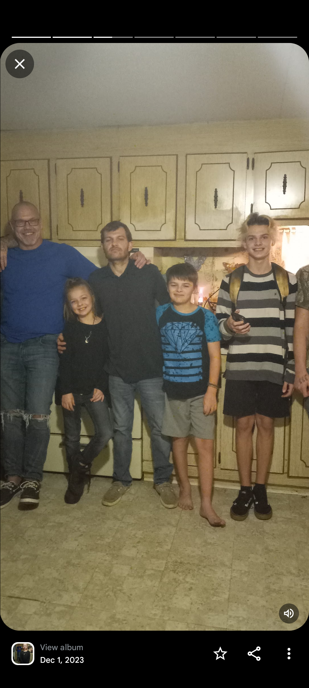 A group of adults and kids share smiles in a cozy home photo.