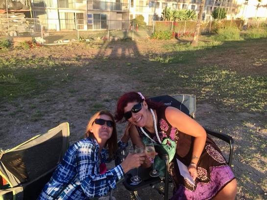 Two friends relax on beach chairs while sharing drinks and enjoying the sunset together.