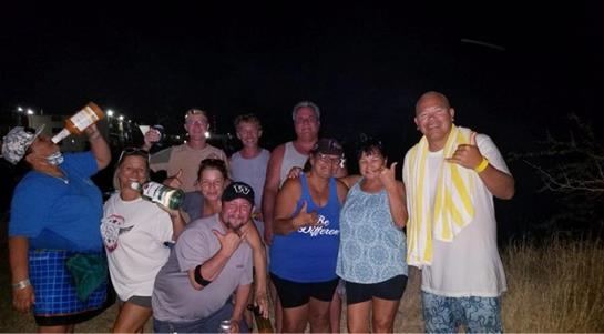Friends gather with drinks under the night sky, enjoying laughter and camaraderie together.