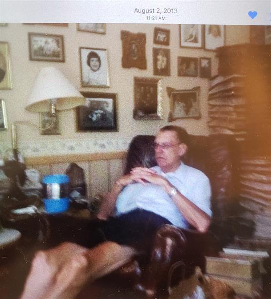 An elderly man relaxes in a comfortable chair amid numerous family pictures and memories.