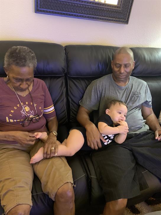 Grandparents spend time with their grandchild, sharing laughter and love on a cozy couch.