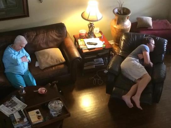 A calm afternoon in the living room where an older woman sits while a younger man relaxes.