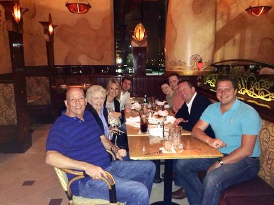 Friends gather around a large table sharing food and laughter at a restaurant during dinner.