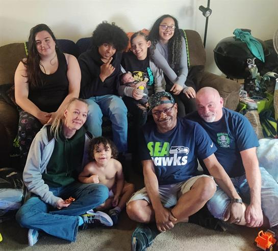 Seven family members of different ages relax and laugh together in a cozy living room.