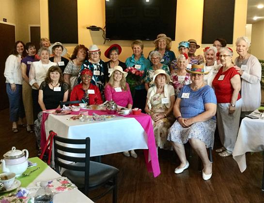 Women of various ages enjoy a festive tea party filled with laughter and conversation.
