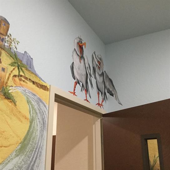 A colorful mural of two birds brightens the entrance wall, enhancing the room's ambiance.