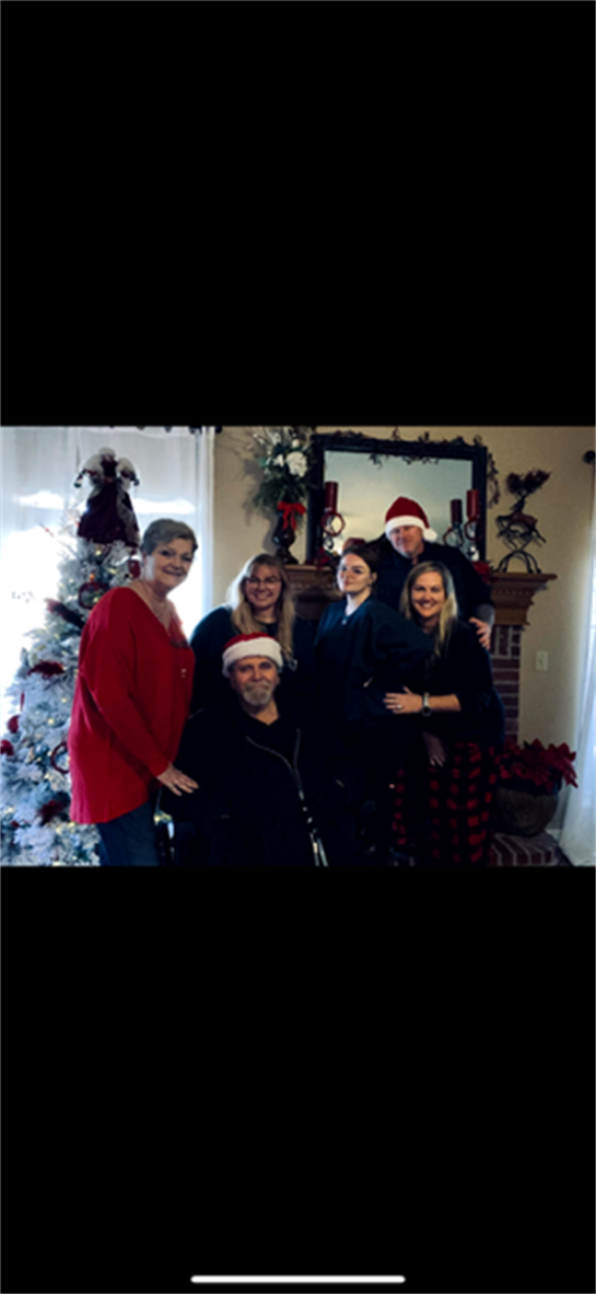 Group of family members celebrating Christmas in a decorated living room with a tree.