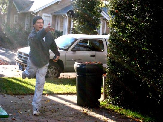 A man throwing leaves in the trash