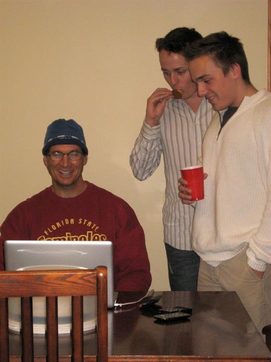 A group of men standing around a laptop