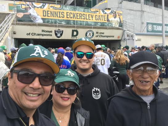 Family poses for a cheerful group selfie while entering the Oakland Athletics stadium.