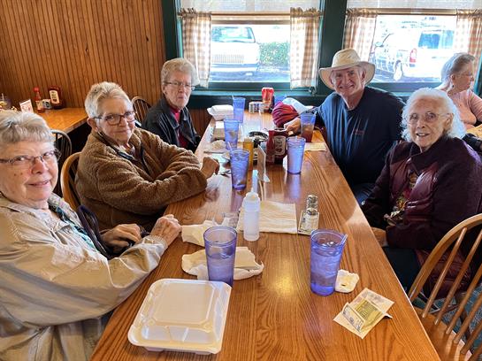 A group of five friends gathers around a wooden table, sharing stories and laughs.