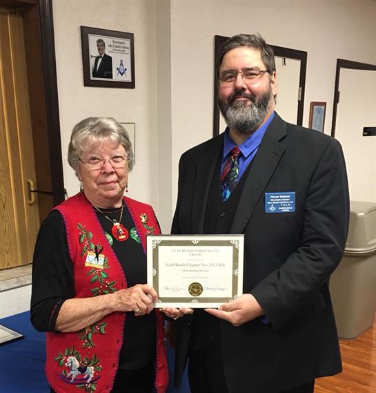 A woman and man celebrate an award presentation during a community gathering in a hall.