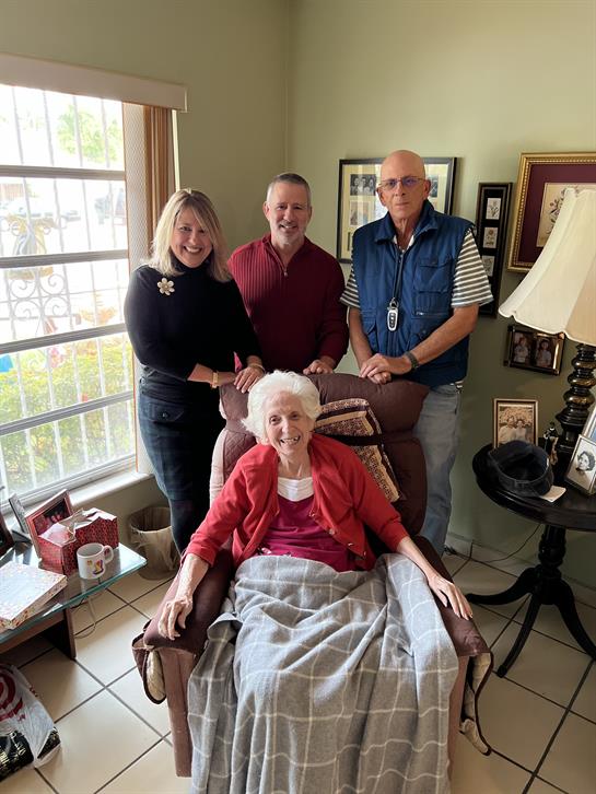 A cheerful family visit in a bright living room with an elderly woman and her adult children.