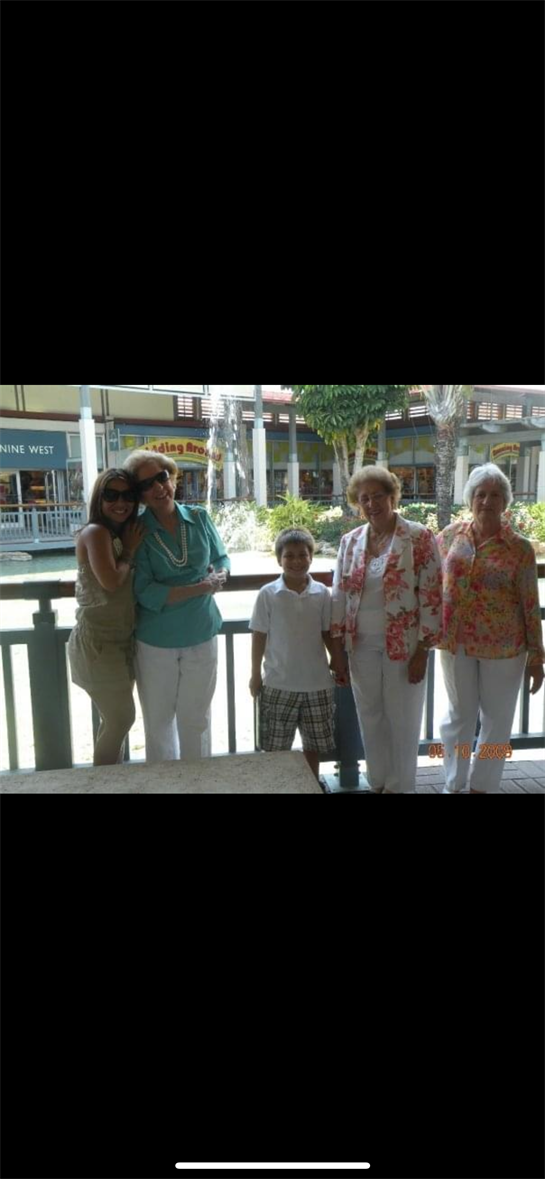 Five family members gather for a joyful moment at a sunny outdoor shopping area.