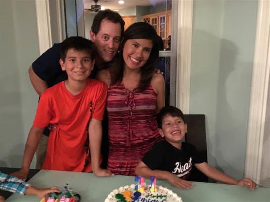 A family enjoys a joyful celebration together with a birthday cake and balloons.