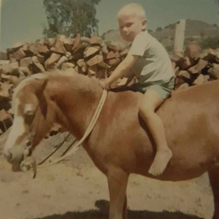 A baby sitting on a horse