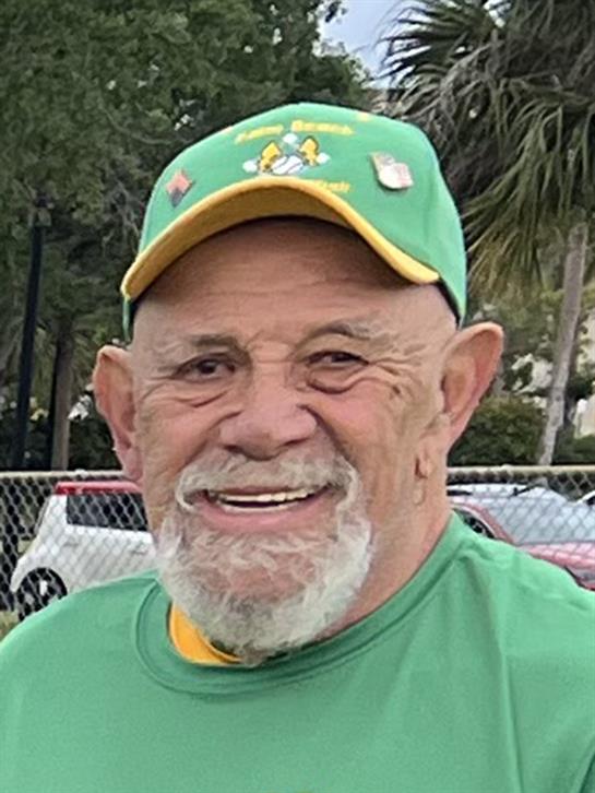 Cheerful older man enjoys an outdoor event while proudly sporting a vibrant green cap.
