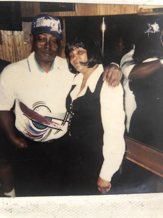Two individuals share a joyful moment, posing closely in a bar filled with energy and chatter.