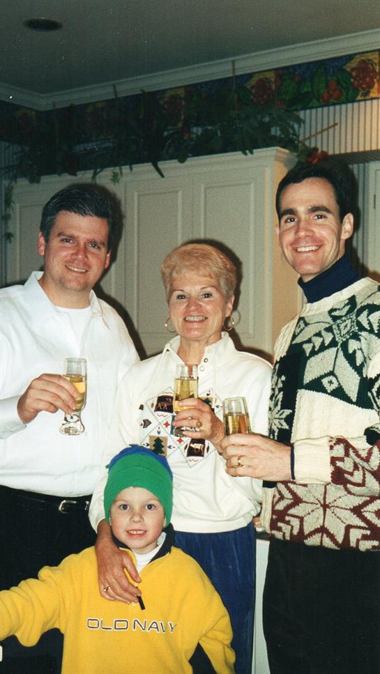 Four family members raise glasses in a warm kitchen, celebrating together with joy and laughter.