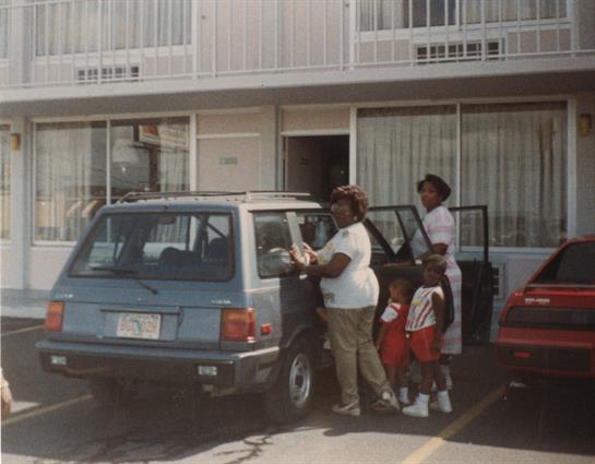 A family loads their car outside a hotel, ready to start their next adventure together.