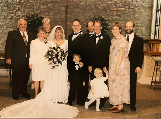 A group of people dressed in formal attire celebrates a wedding with laughter and smiles.