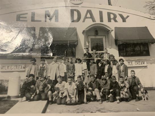 Community members pose happily outside Elm Dairy, showcasing a spirited gathering.