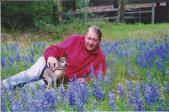 A man enjoys a peaceful moment lounging among blooming bluebonnets with his dog.