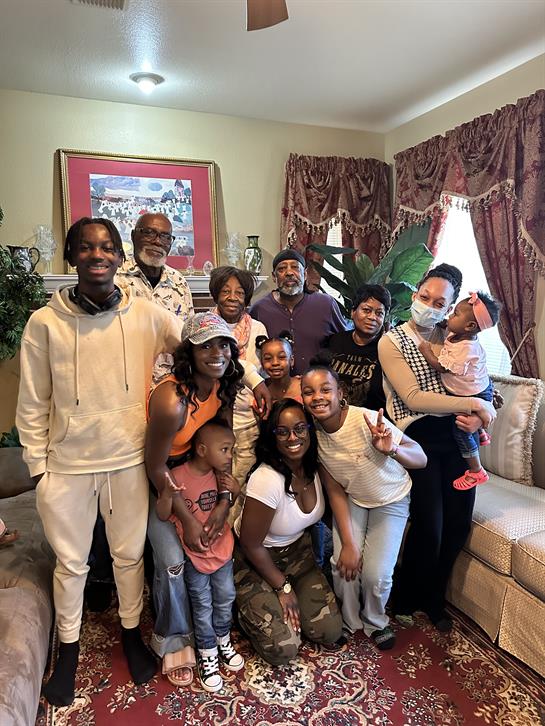 A large family gathers to celebrate and enjoy each other's company in a warm living room.