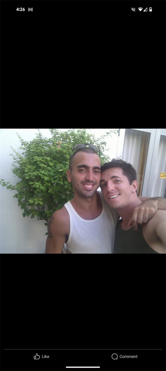 Two friends share a joyful moment, embracing outdoors surrounded by greenery.