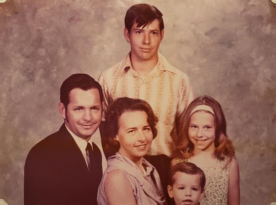 Smiling family poses together in a vintage indoor setting, creating a timeless memory.
