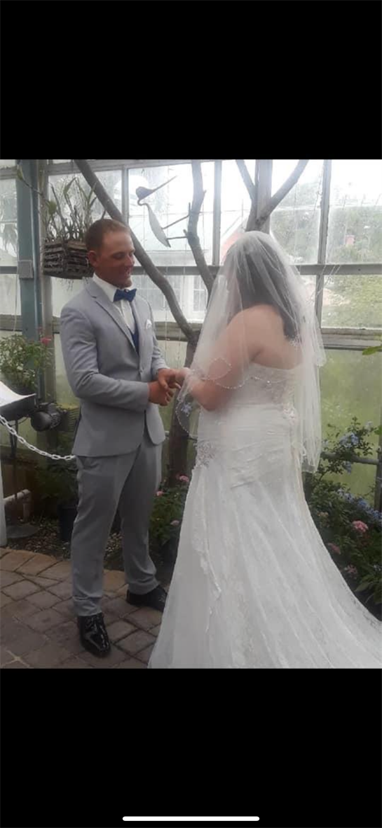 A couple exchanges vows in a beautifully decorated greenhouse during a wedding ceremony.
