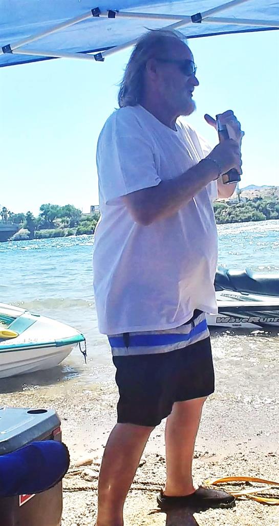 A man standing on a beach holding a bottle of water
