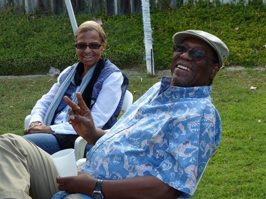 Friends relax and share laughter under the sun on a grassy area, enjoying each other's company.