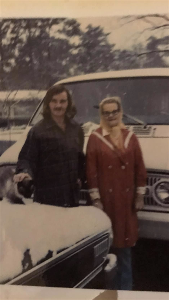 A couple of people standing in front of a car