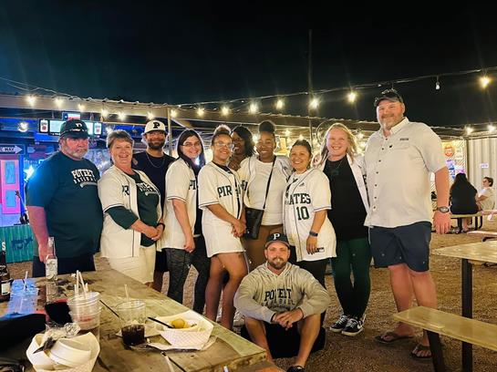 Friends celebrate together at night in team shirts, sharing laughter and creating memories outdoors.