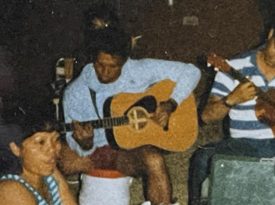 Friends gather together, playing instruments and sharing laughter in a cozy atmosphere.