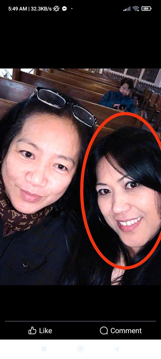 Two women pose closely together, smiling happily inside a church with wooden decor.