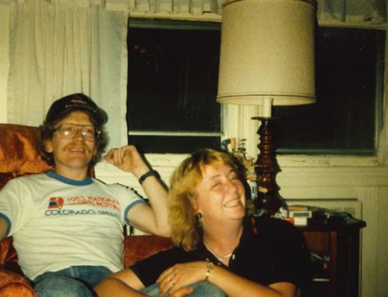 Friends are smiling and engaging in conversation while seated in a cozy and furnished living space.