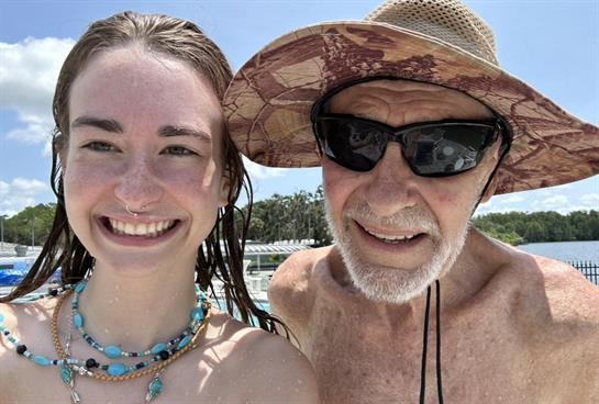 A happy bonding moment between a grandfather and granddaughter by the pool, enjoying sunshine.